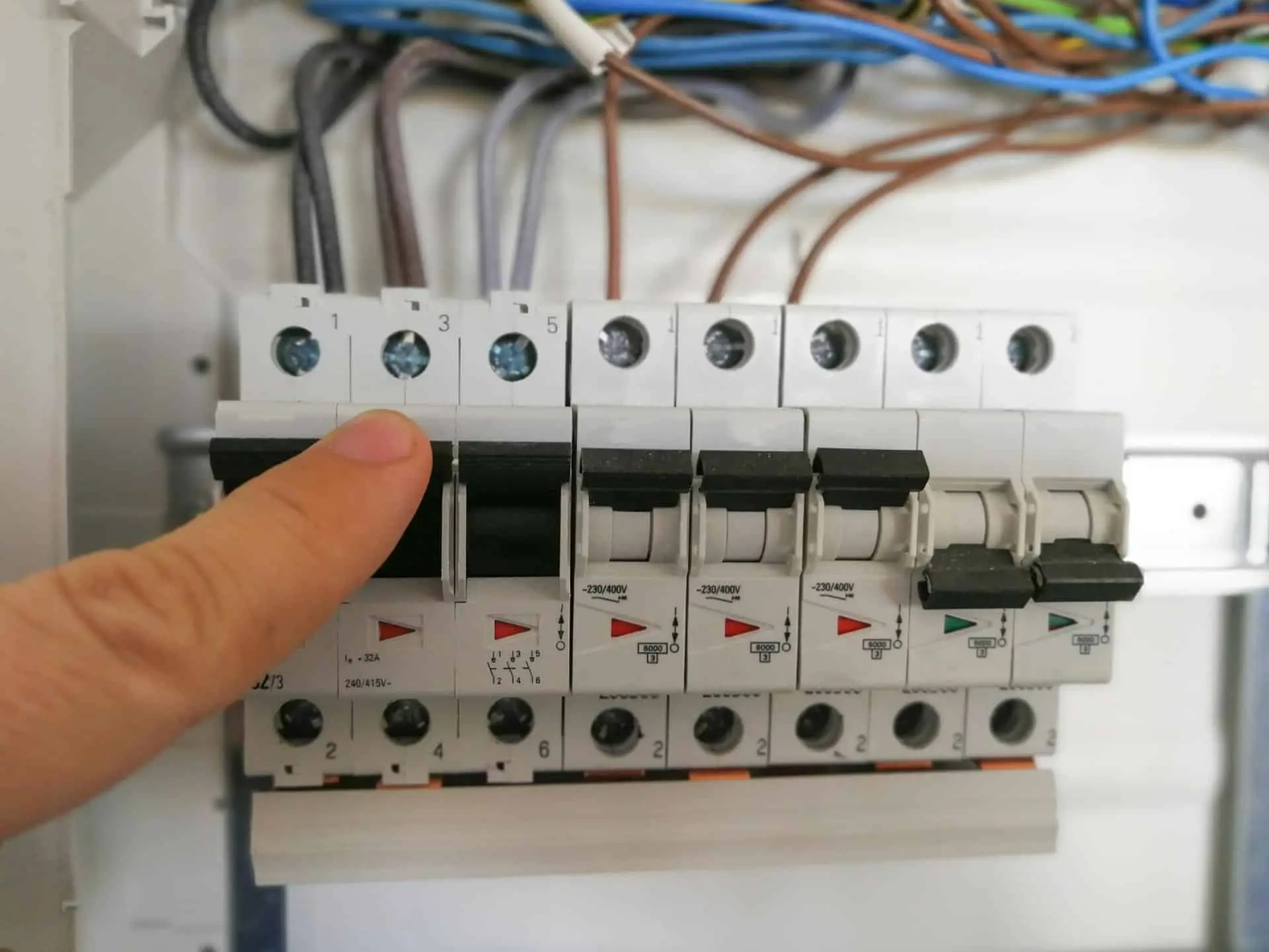Hånd der betjener automatsikringer i en eltavle